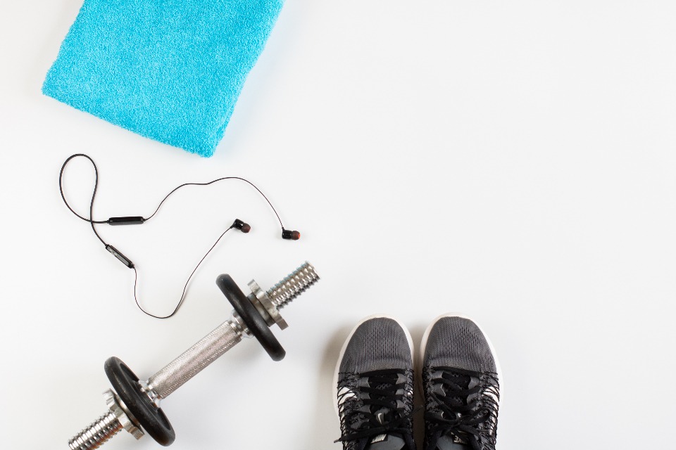 Dumbbell, headphones and sneakers on a white floor