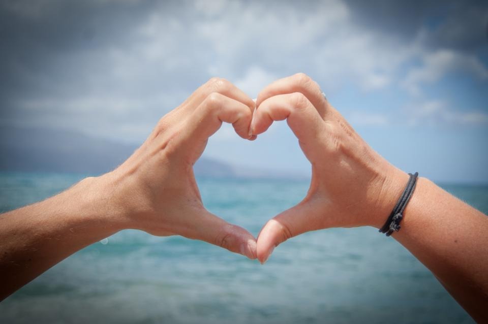 Hands making a heart shape against the sky