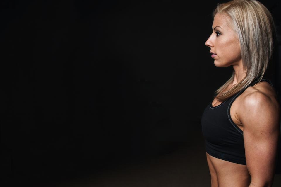 Muscular woman athlete in dark studio light