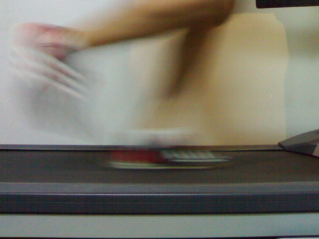 Runner's feet moving fast on a treadmill belt