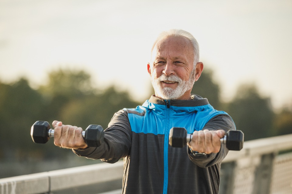 Older man training with dumbbells outdoors