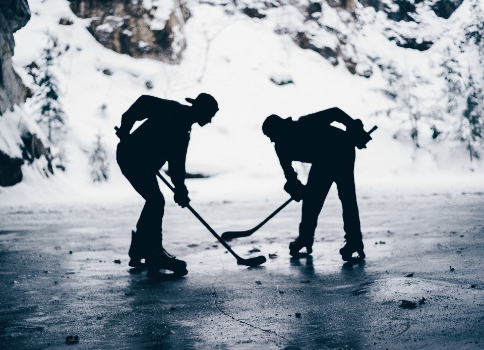 Two hockey players on an outdoor rink at dusk
