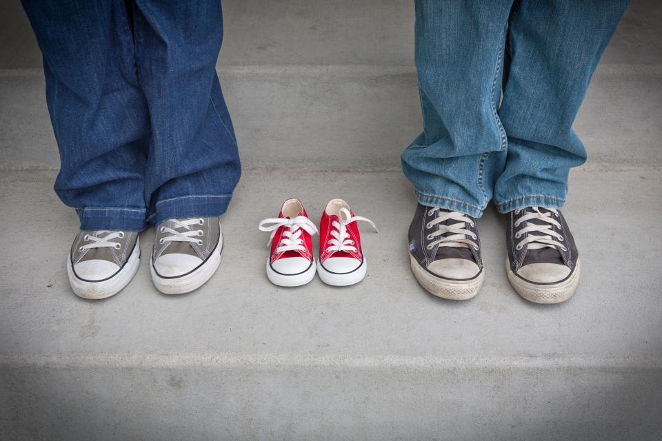 Parents standing beside a pair of baby shoes