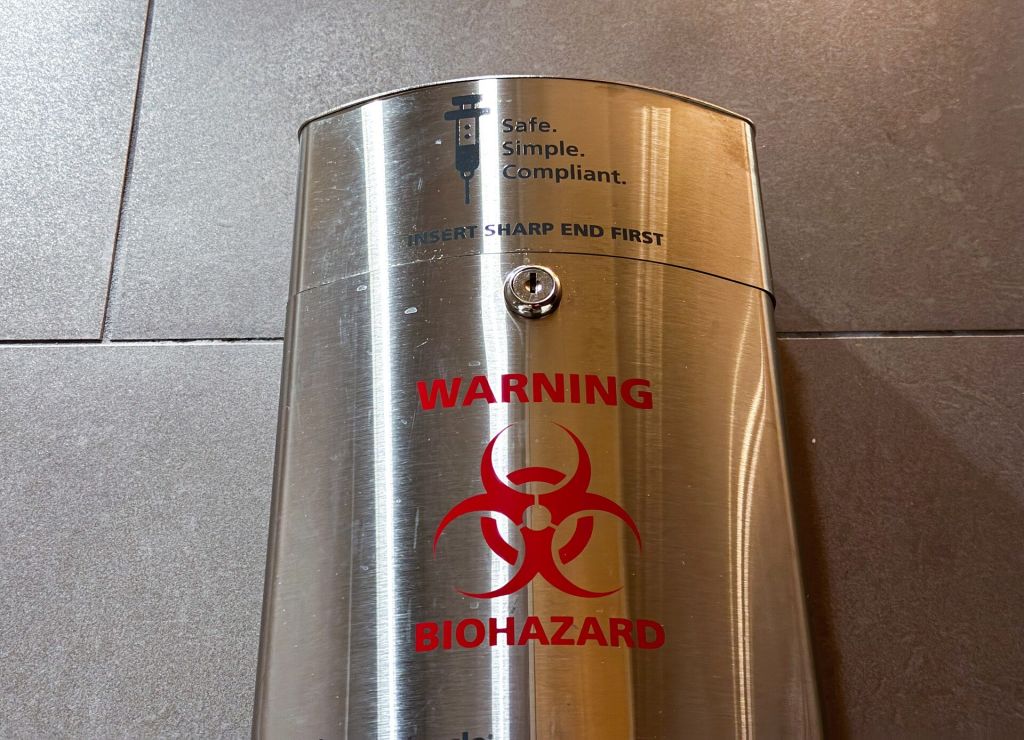 Sharps container with a biohazard warning label