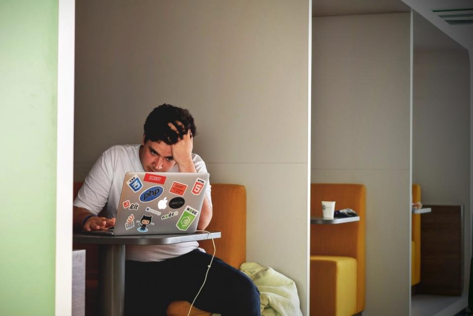 Stressed man with his hands on his head at a laptop