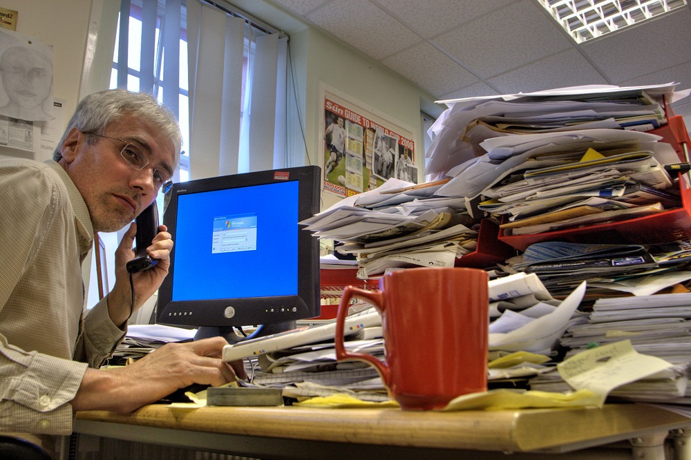 Man working late at a cluttered desk on the phone